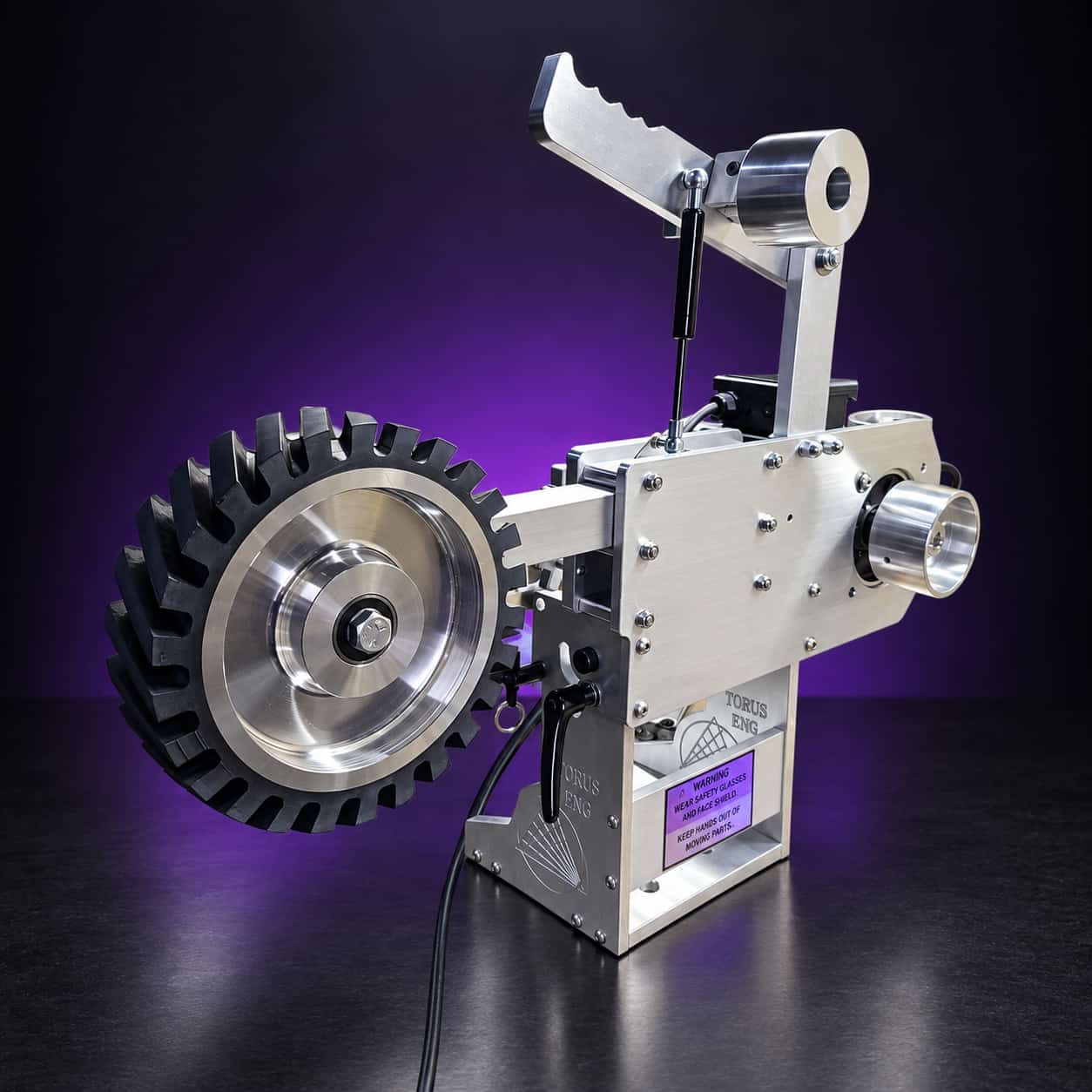 Grinder with a serrated rubber contact wheel, gas-spring tensioner and drive wheel, no belt, on black with a purple glow