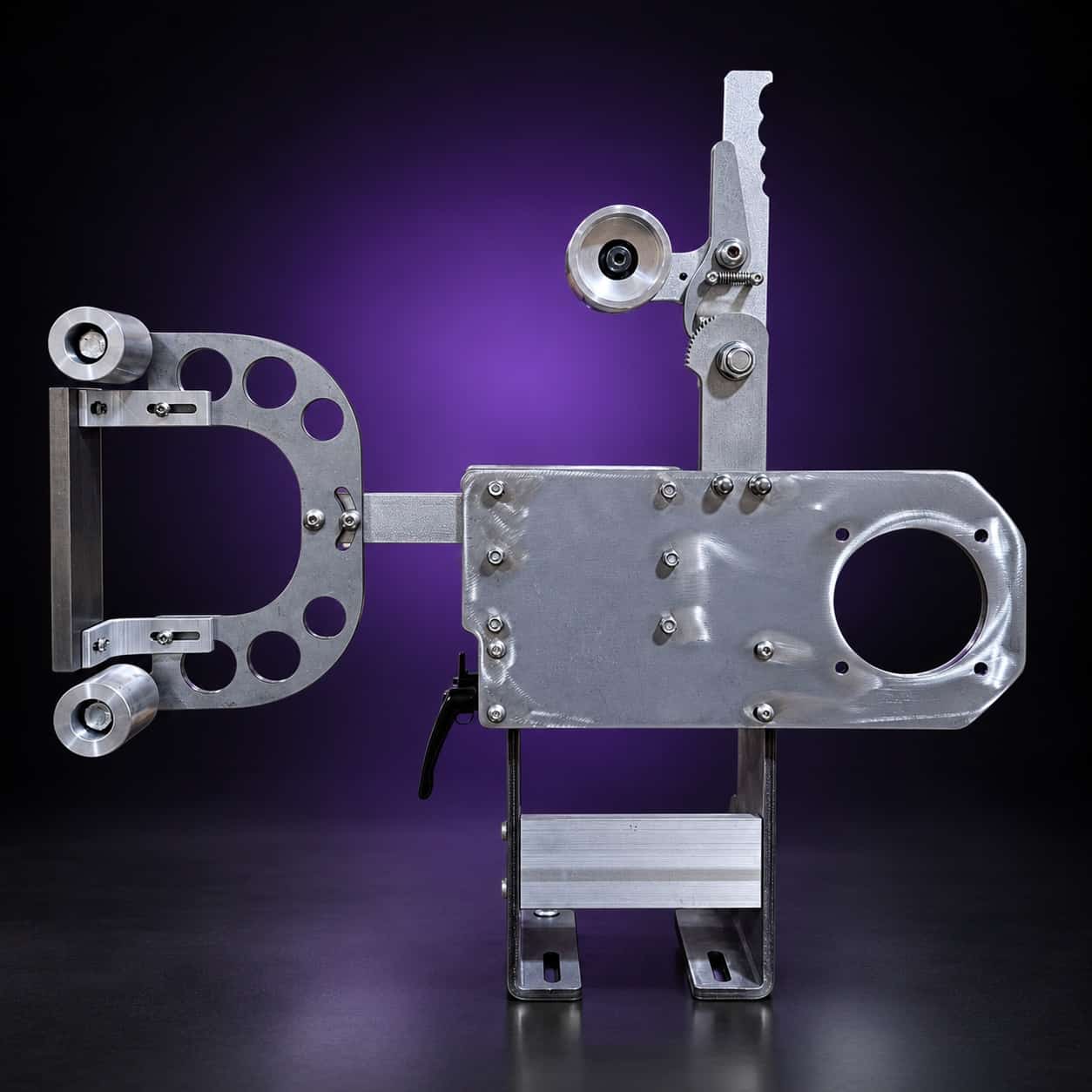 Torus steel 2x72 grinder, side view: drilled arm left, motor plate right, lever on top, on black with a purple glow