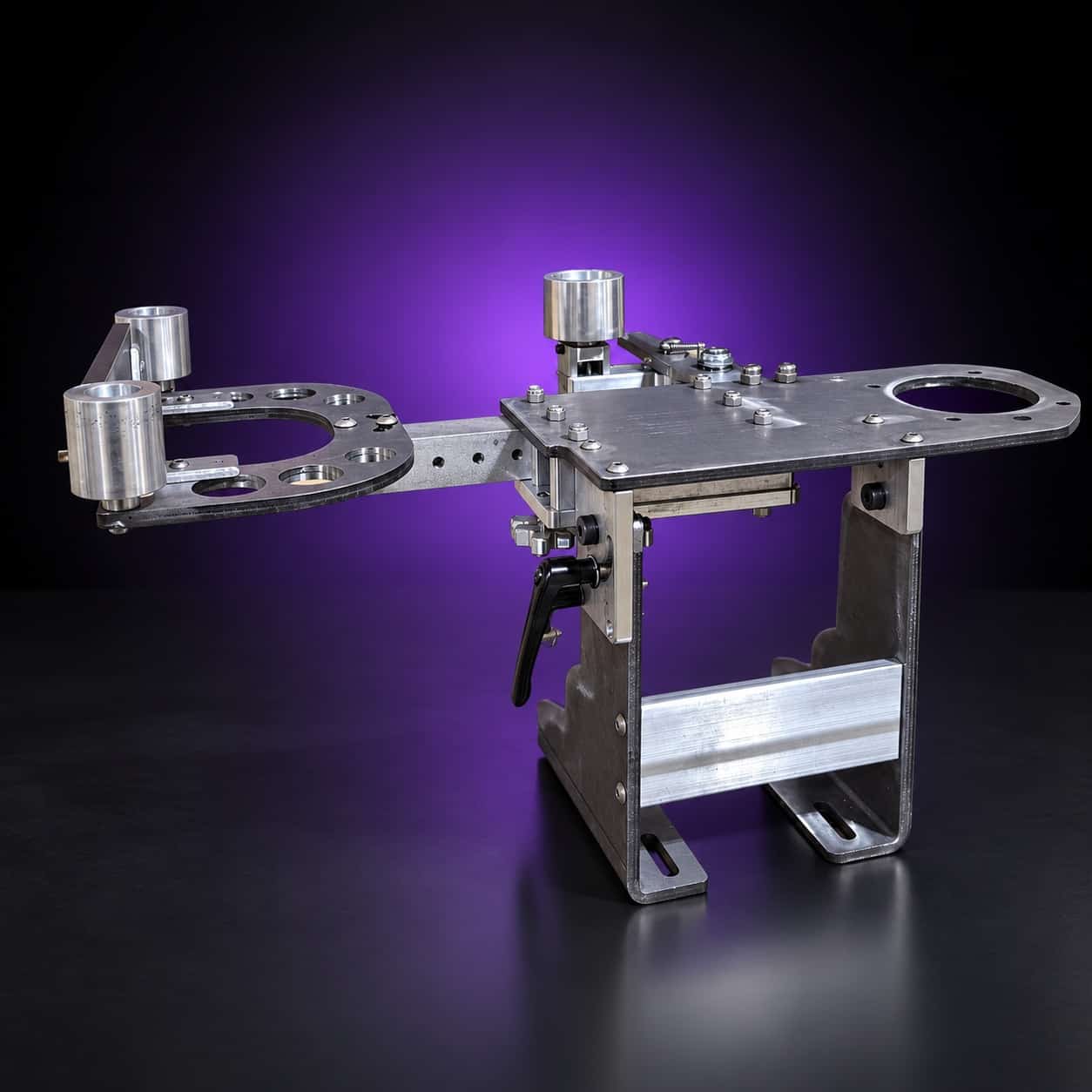 Torus steel 2x72 grinder laid horizontal, motor plate up, drilled arm with idlers at left, on black with a purple glow