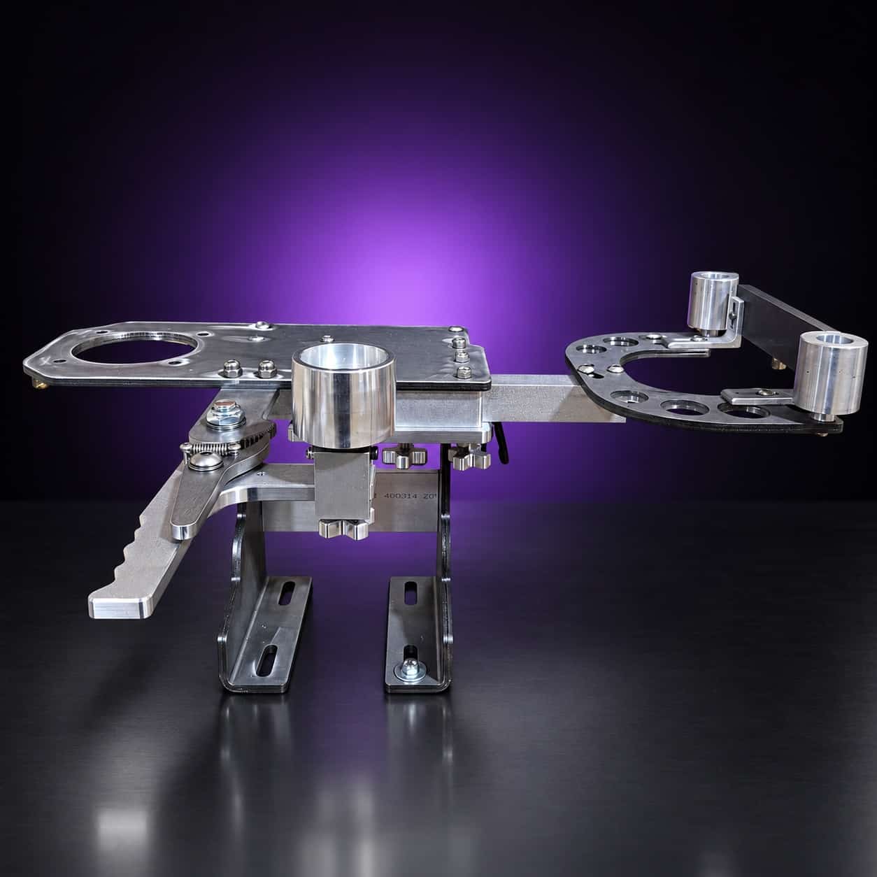 Torus steel 2x72 grinder laid horizontal, three-quarter view from the tension-lever side, on black with a purple glow