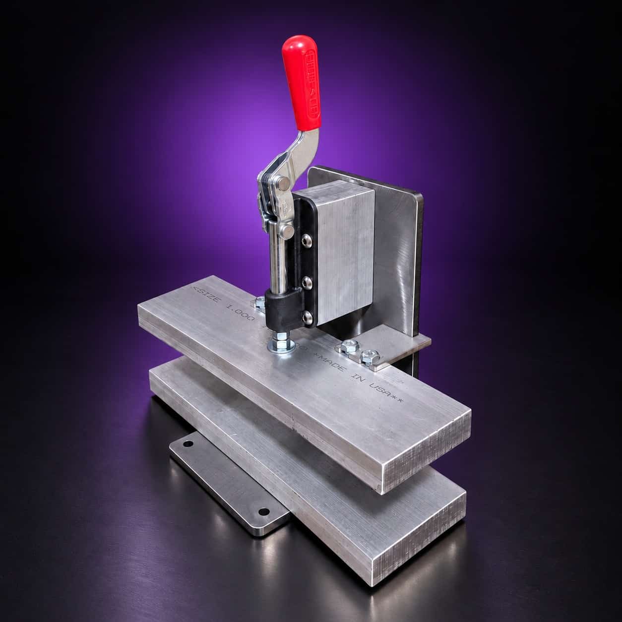 Quench vise with the red toggle clamp raised (open) over two thick aluminum plates, on black with a purple glow
