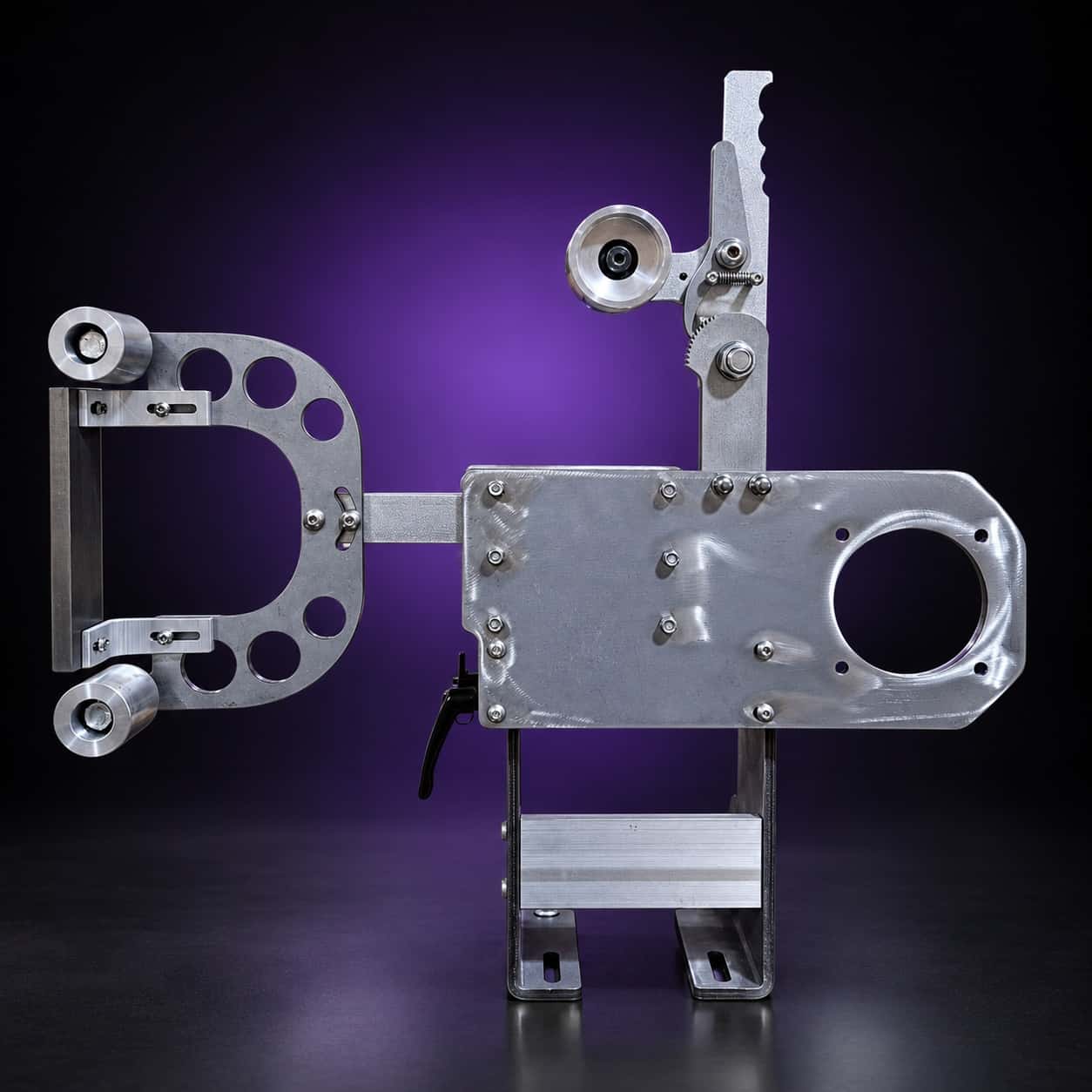 Torus steel 2x72 grinder, side view: drilled arm left, motor plate right, lever on top, on black with a purple glow