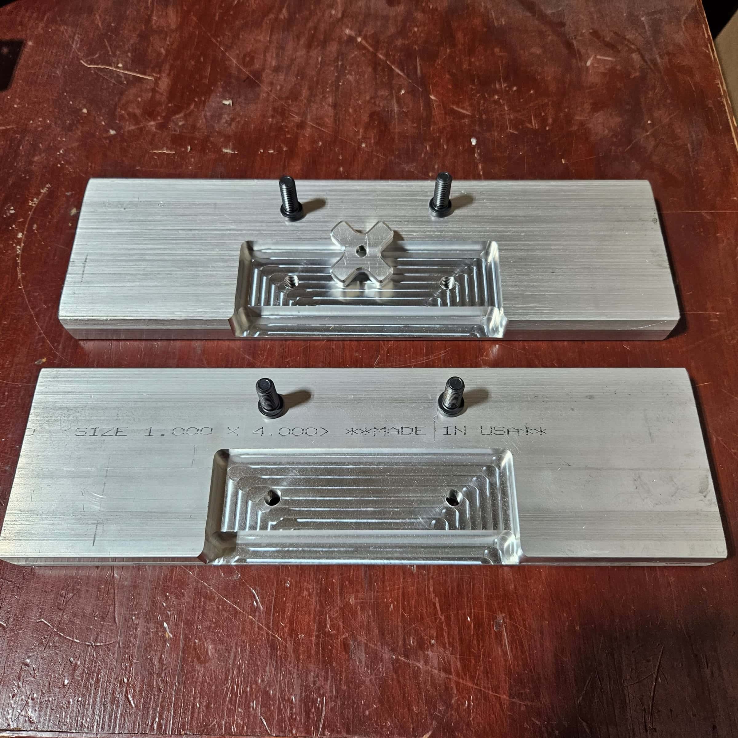 Two aluminum quench plates engraved Made in USA, with the X-shaped alignment key between them