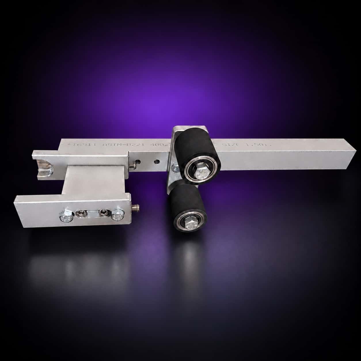 Small wheel attachment from above: holder fork, engraved aluminum arm and two rubber wheels, on black with a purple glow