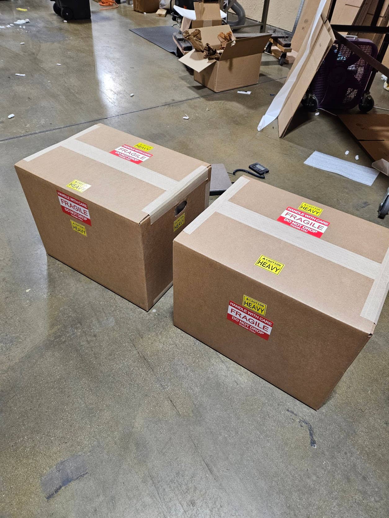 Two taped cartons marked FRAGILE and HEAVY, holding finished Torus CNC grinders, on the shop floor in Sterling