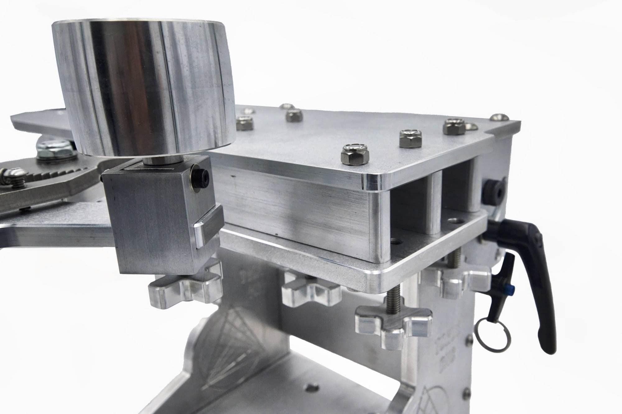 Close-up of hex nuts and cross-knob adjusters securing a wheel mount on a grinder tooling arm