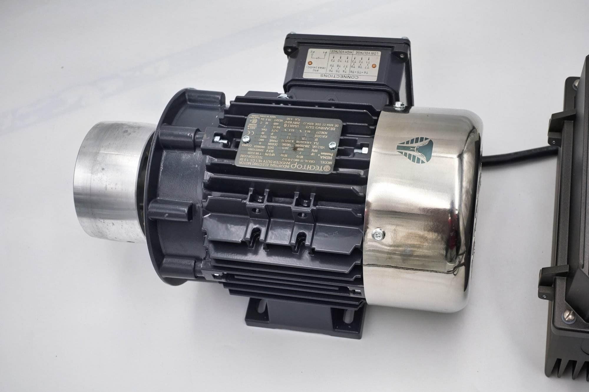Close-up of a TechTop industrial motor's wiring connection box and nameplate on a Torus CNC grinder