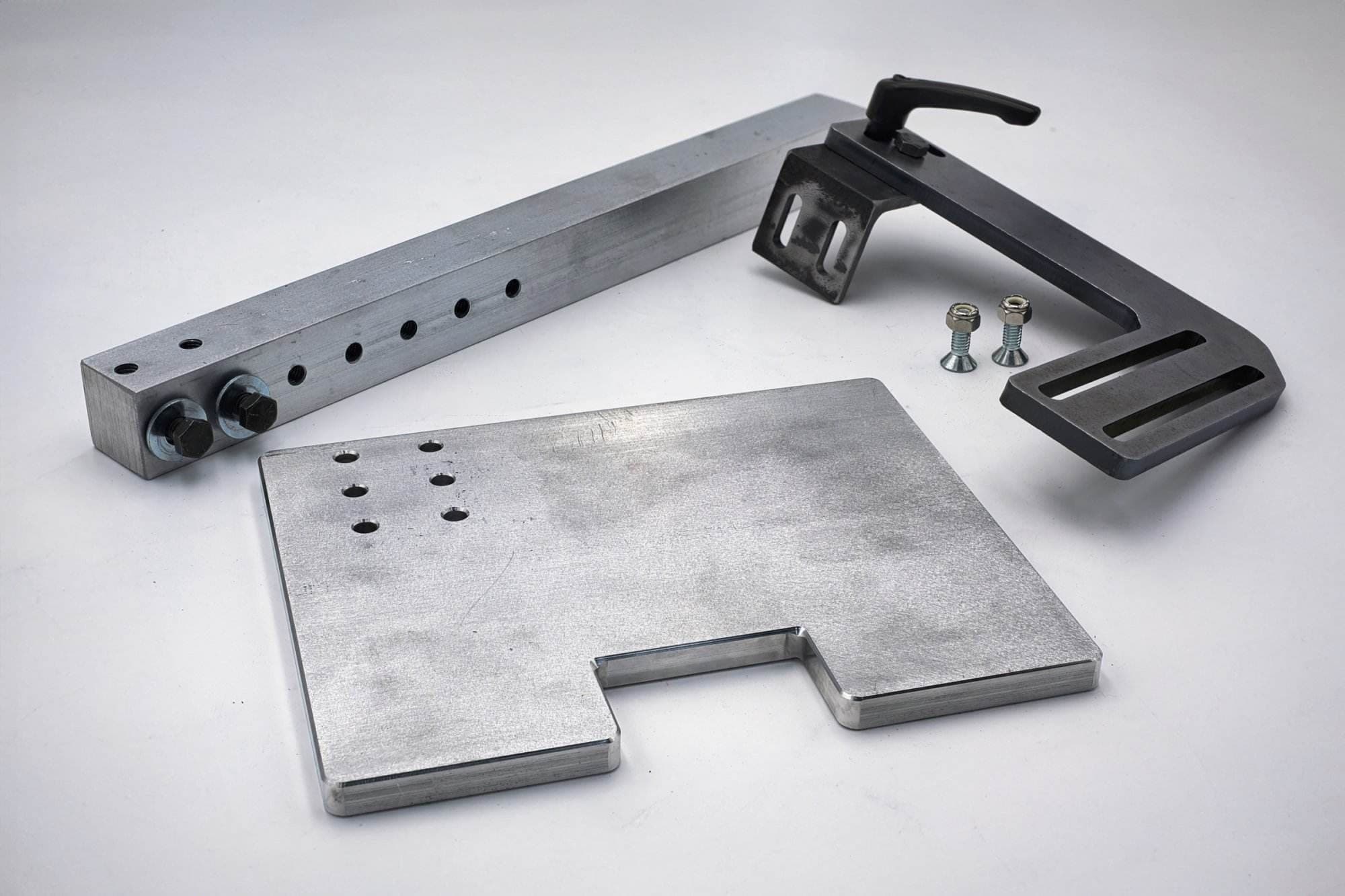 Aluminum tracking bar, black clamp lever assembly, and notched mounting plate laid out unassembled with loose hardware