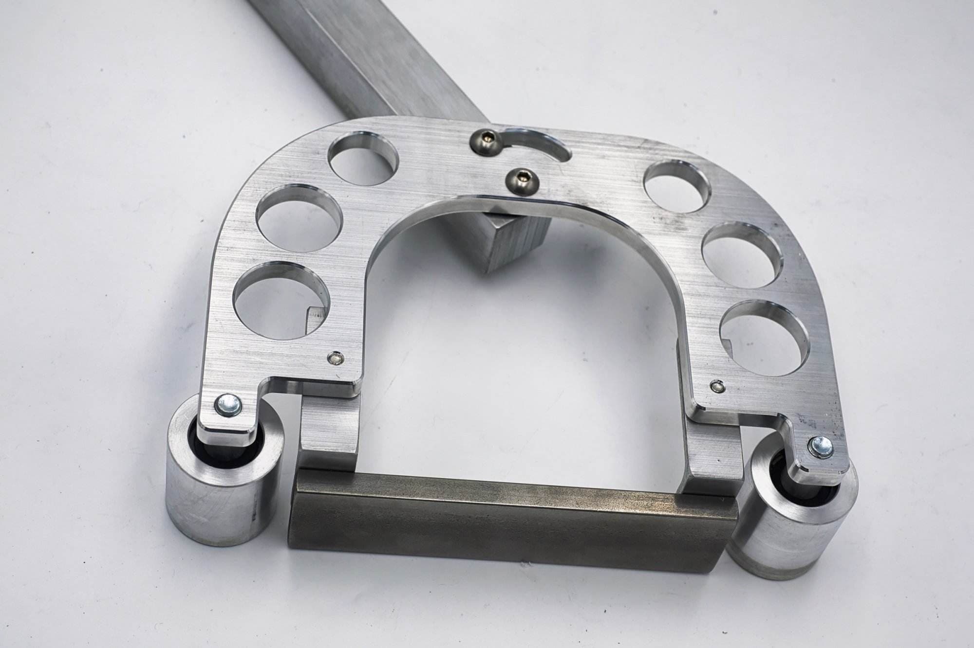 Square aluminum tracking bar, mounting block, and five rubber-coated bearing idler wheels laid out