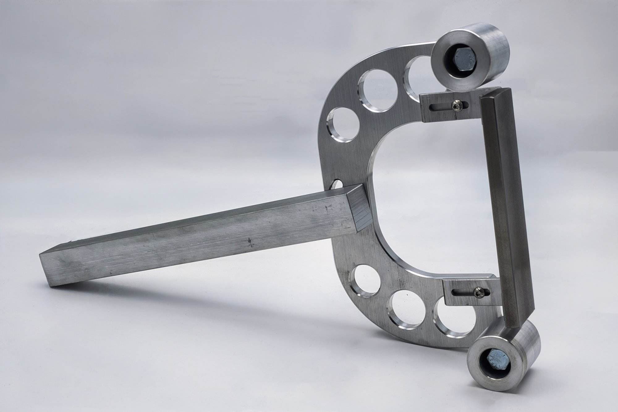 CNC aluminum wishbone bracket with paired roller mounts leaning at an angle beside its square mounting bar