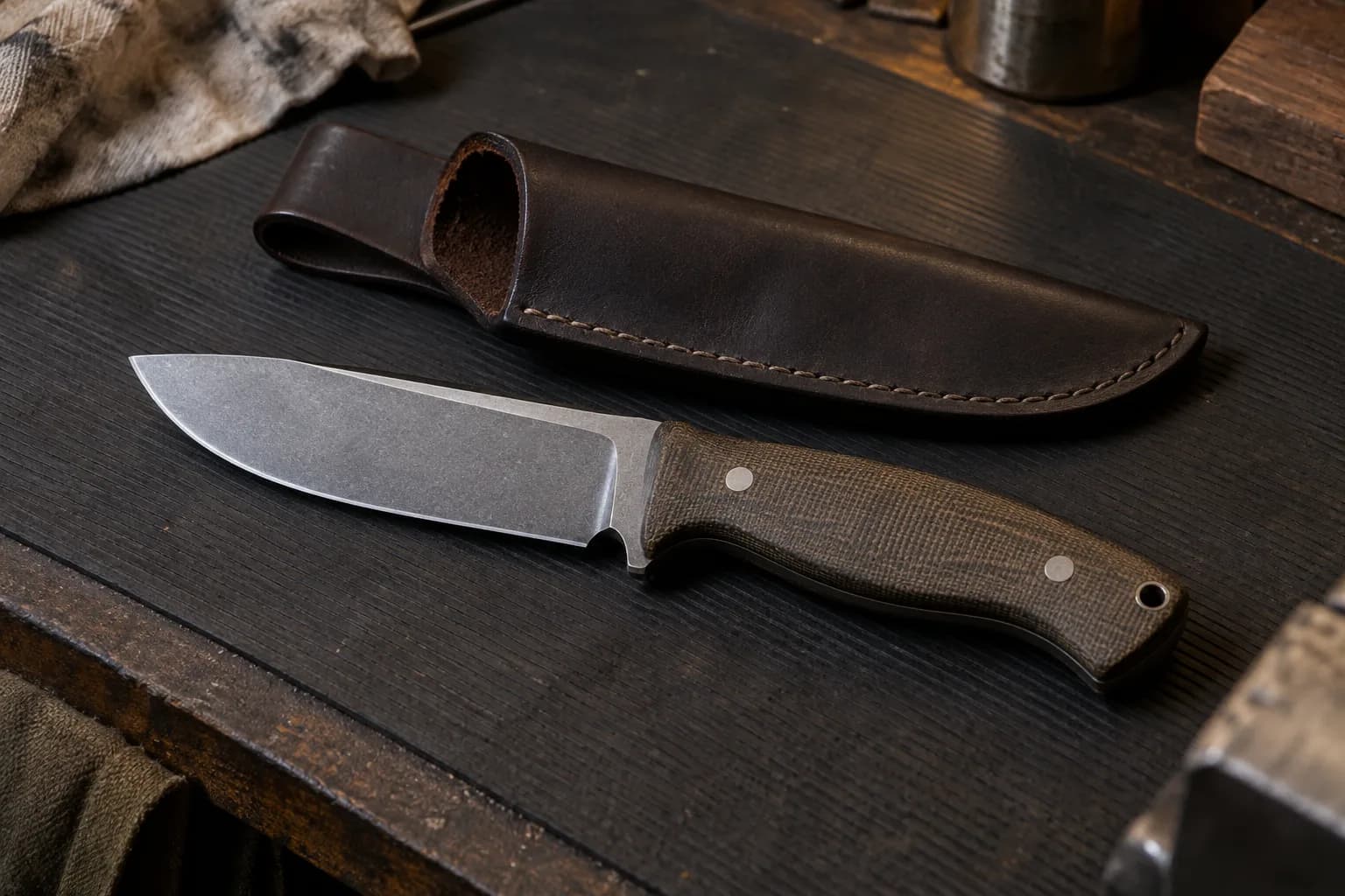 Stout drop-point fixed-blade knife with a green micarta handle lying on a ribbed rubber mat beside a plain brown leather sheath.