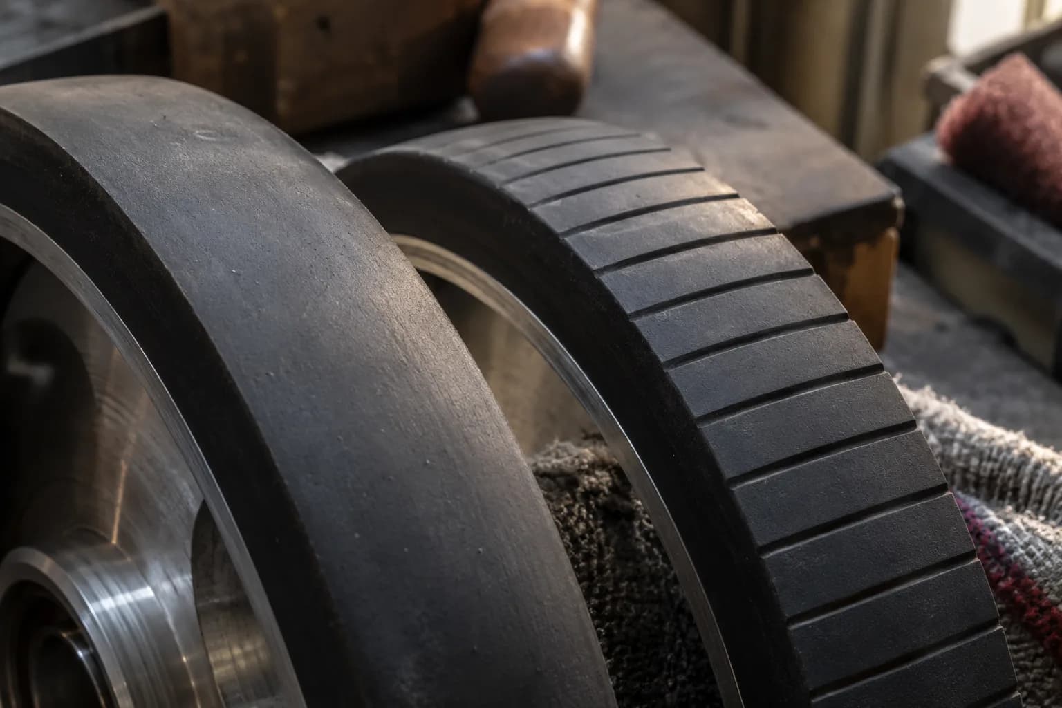 Close view of a smooth rubber wheel tread beside a contact wheel with evenly spaced narrow grooves across its face.