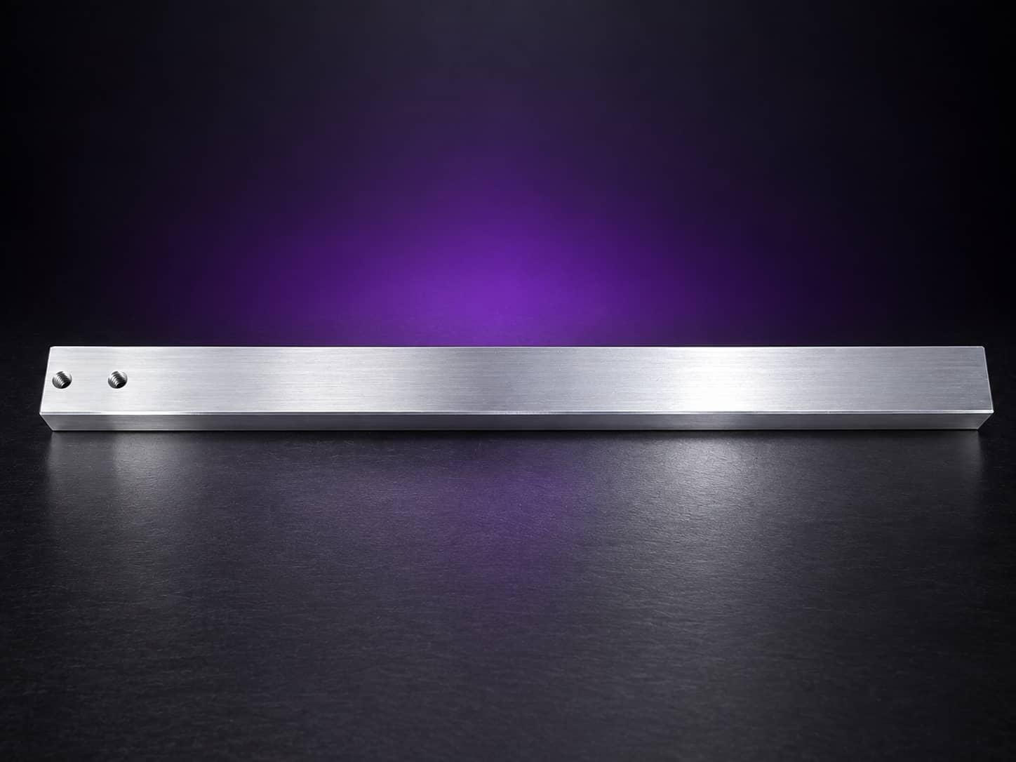 Plain 1.5-inch square aluminum tooling arm with two holes at one end, on black with a purple glow