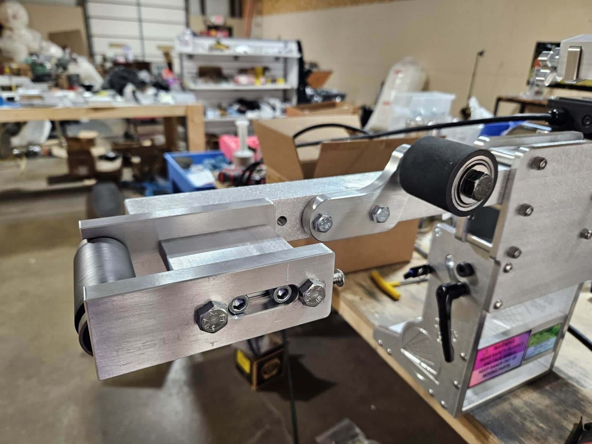 Small wheel attachment mounted on a 2x72 belt grinder inside a cluttered home workshop