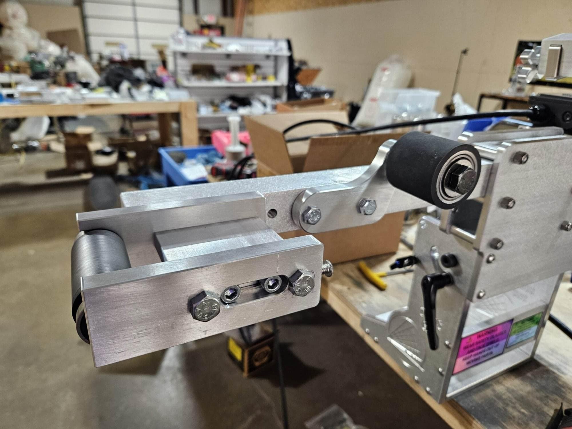 Small wheel attachment mounted on a 2x72 belt grinder inside a cluttered home workshop