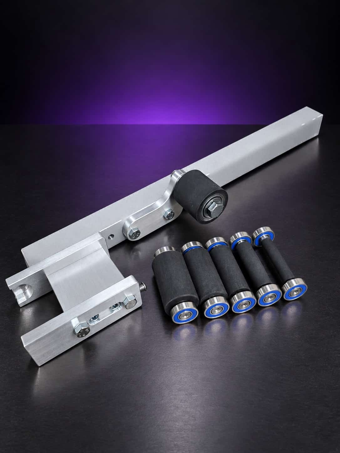 Small wheel attachment arm with five small wheels on blue-shielded bearings, angled from above, on black with a purple glow