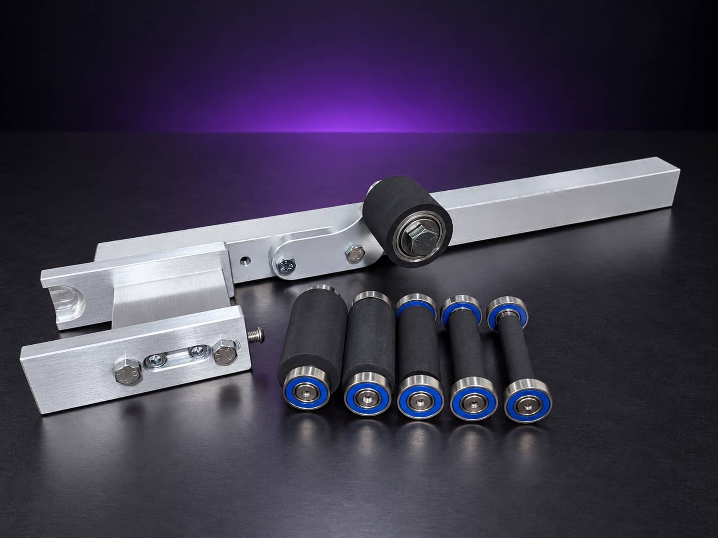 Small wheel attachment kit laid out: arm, holder, side plate, idler roller and five wheels, on black with a purple glow