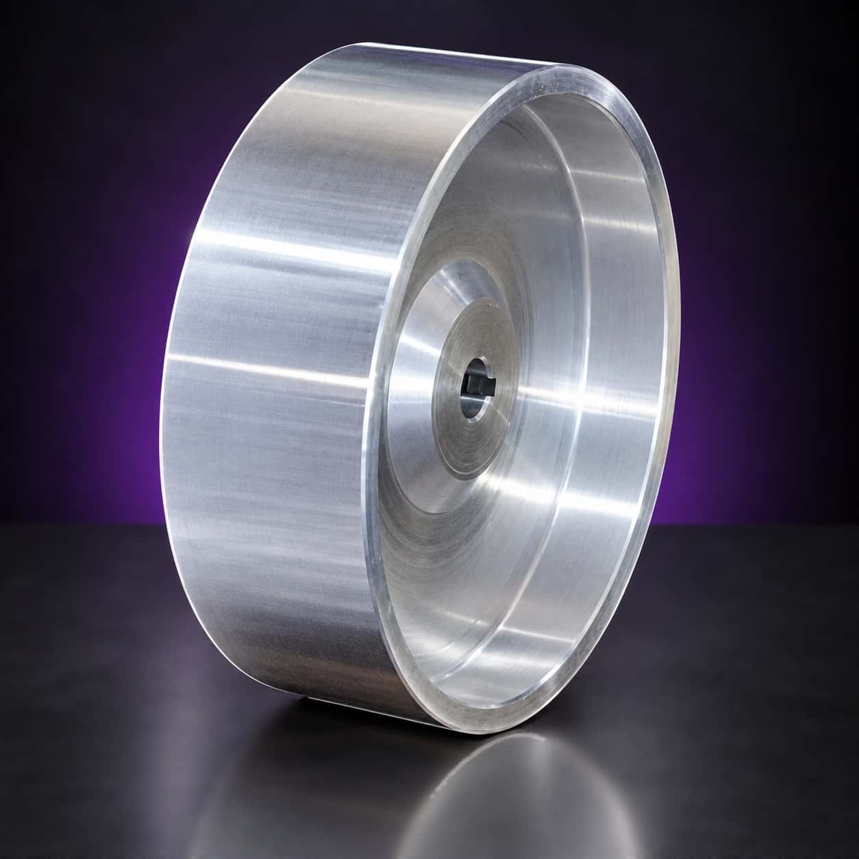 Polished aluminum drive wheel with keyed bore, three-quarter view of the dished face, on black with a purple glow
