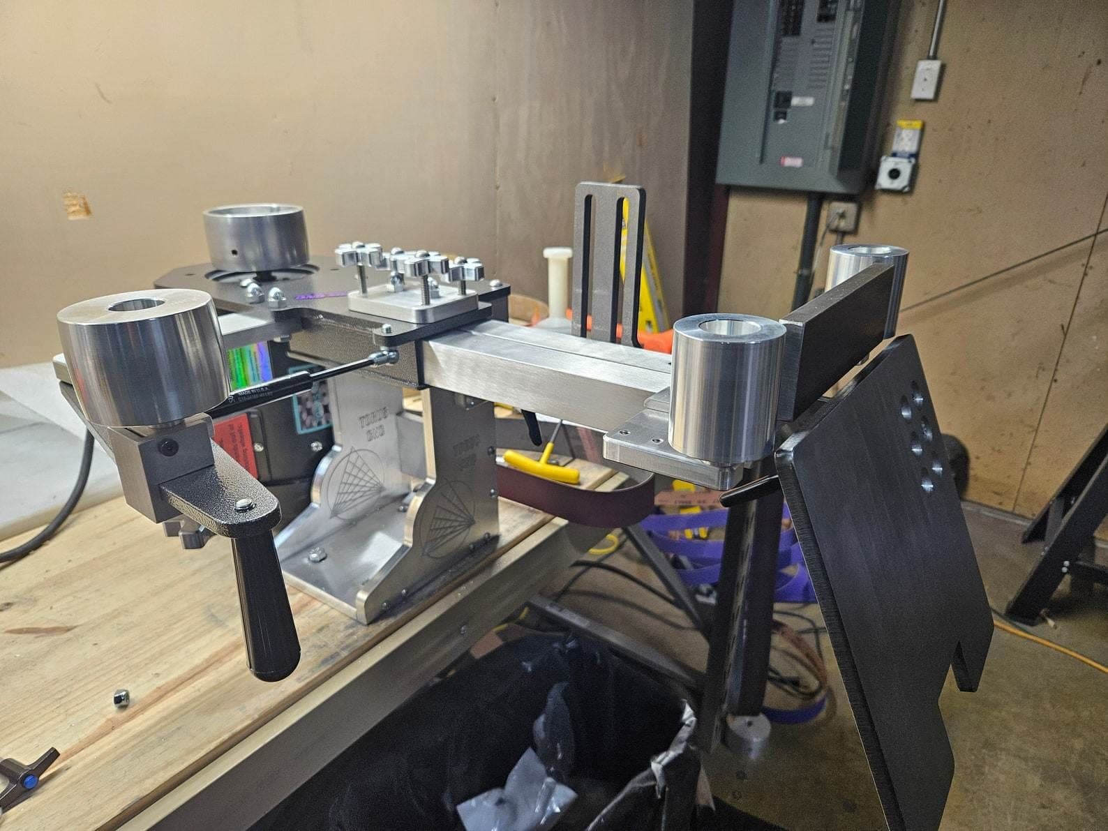 Grinder tooling arm with drive and idler wheels mounted on a stand inside the Torus CNC shop