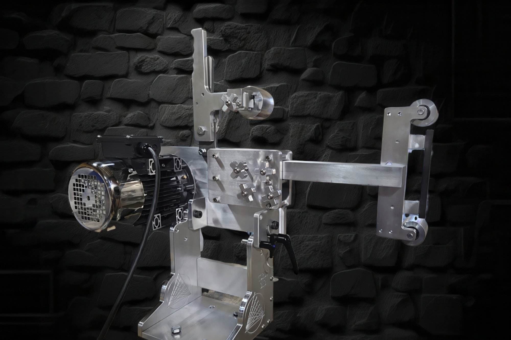 M90 aluminum belt grinder with small wheel attachment posed against a dark stone wall backdrop
