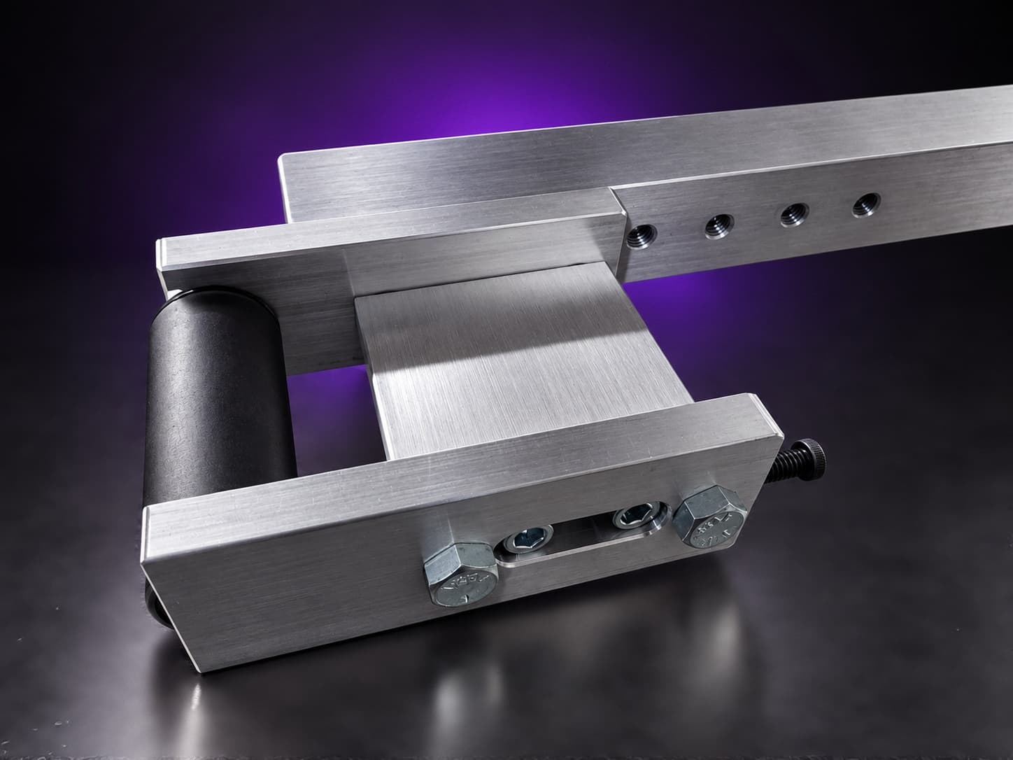 Small wheel attachment: aluminum holder and black rubber wheel at the end of the tool arm, on black with a purple glow