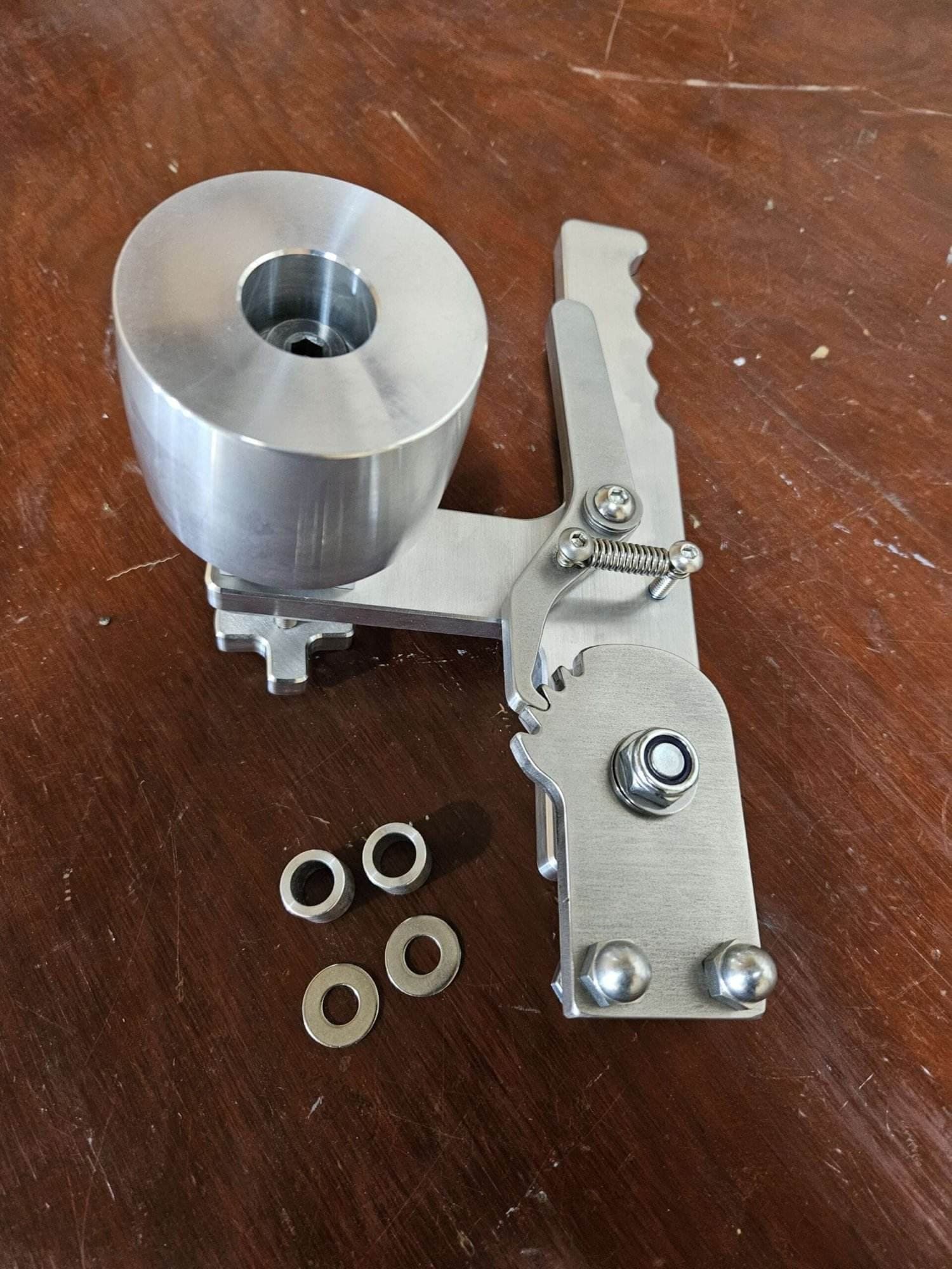 Aluminum tooling arm with four rubber-coated idler wheel bearings laid out on a wood bench