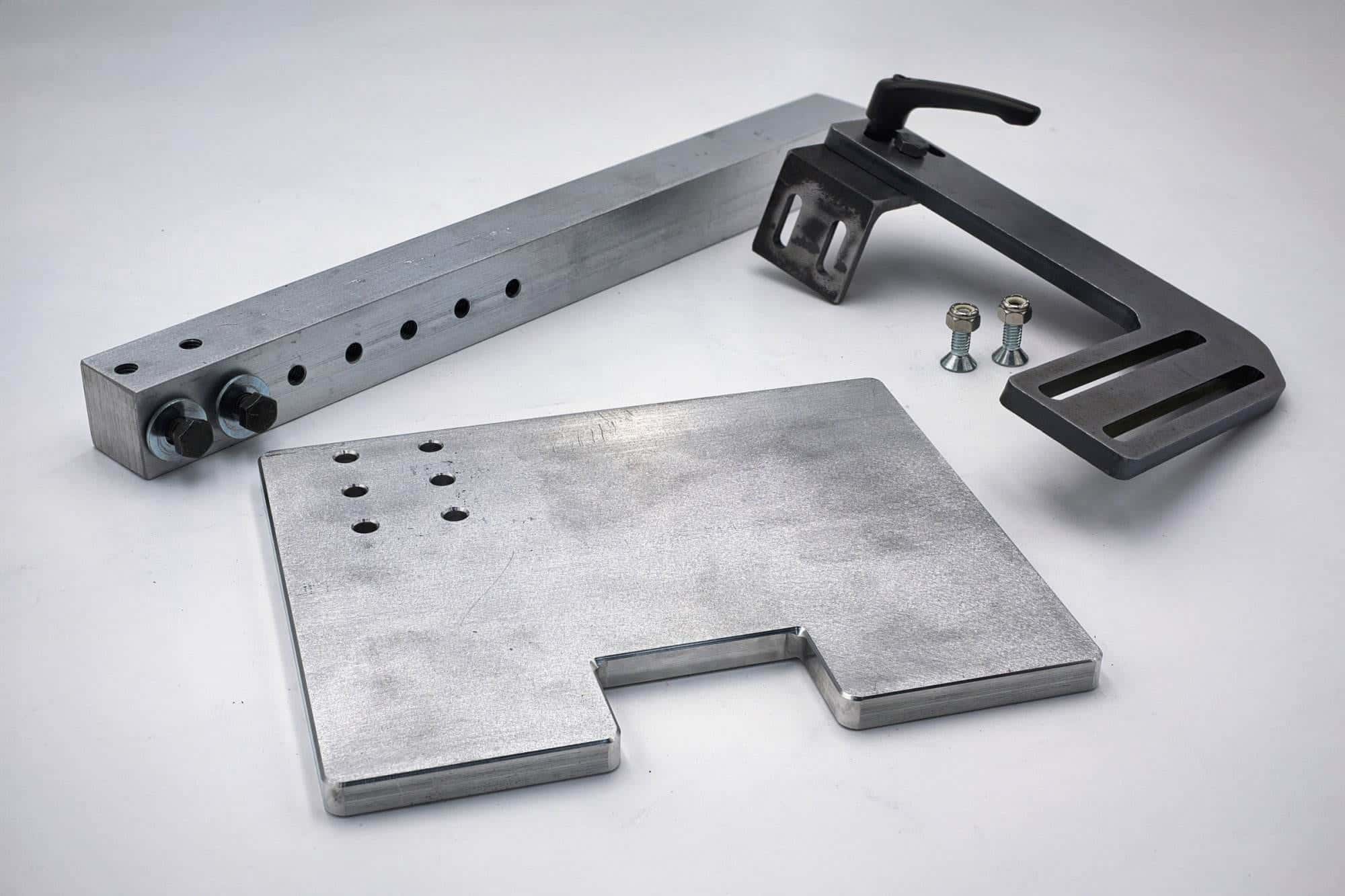 Aluminum tracking bar, black clamp lever assembly, and notched mounting plate laid out unassembled with loose hardware