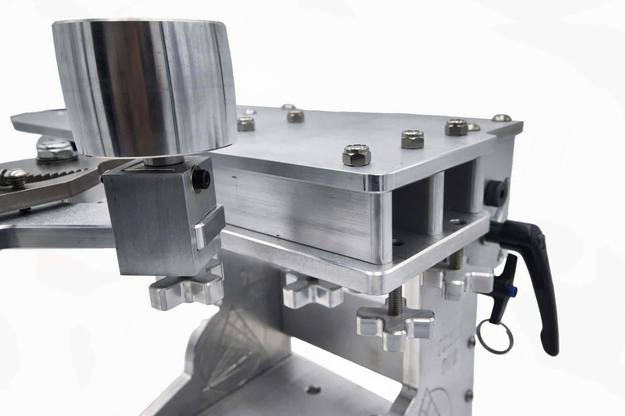 Close-up of hex nuts and cross-knob adjusters securing a wheel mount on a grinder tooling arm