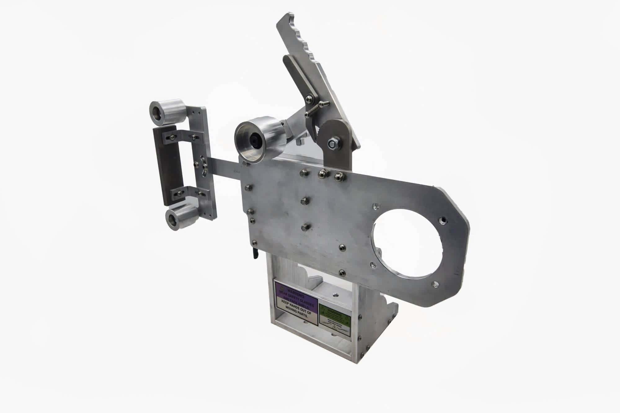 Base of a Torus CNC tooling arm frame showing riveted safety warning labels and mounting bolts