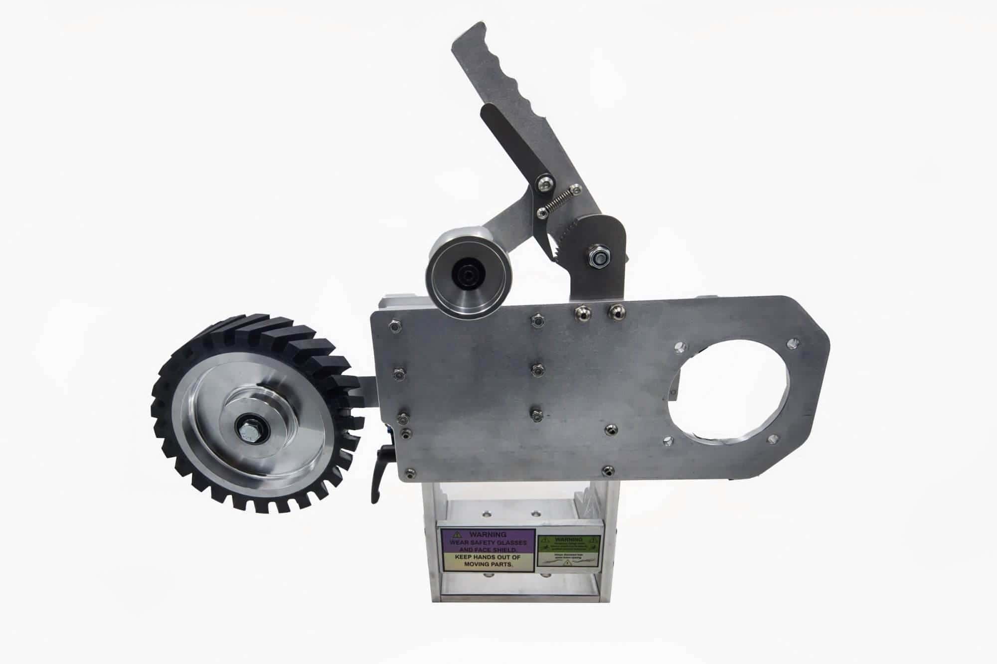 Toothed rubber drive wheel mounted on a Torus CNC 2x72 grinder tooling arm with warning stickers