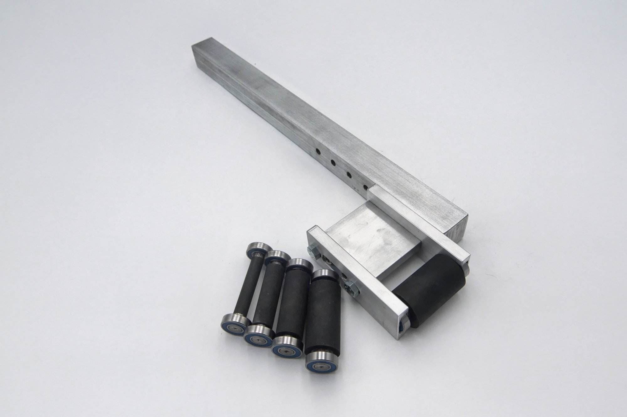 2x72 grinder arm assembly beside a loose contact wheel and four rubber-coated tracking rollers