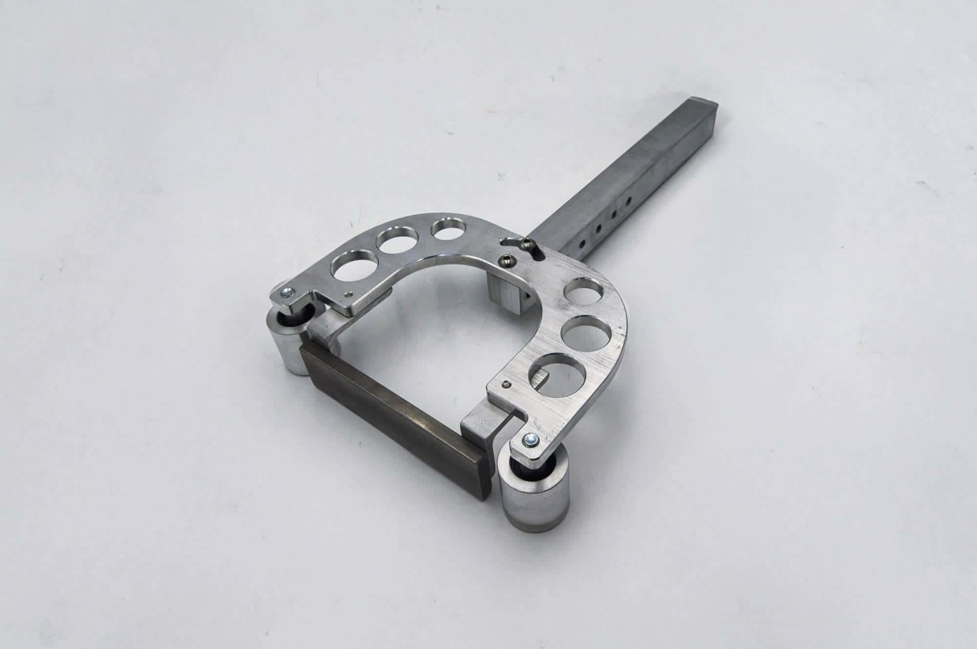 Machined horseshoe-shaped bracket with mounting holes and dual roller bearings for a grinder arm