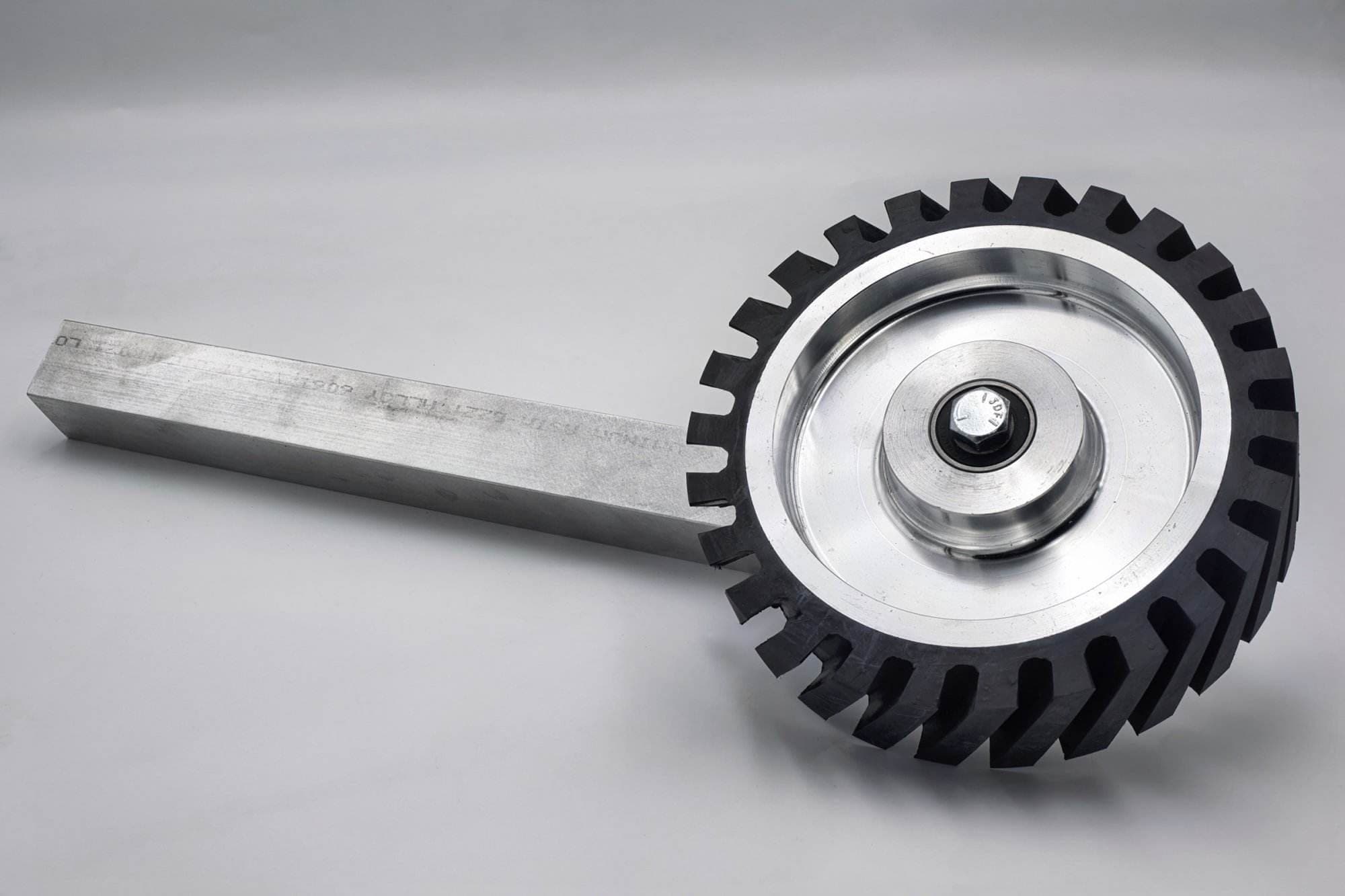 Rubber-toothed grinder wheel and aluminum shaft photographed with a visible mill certification stamp