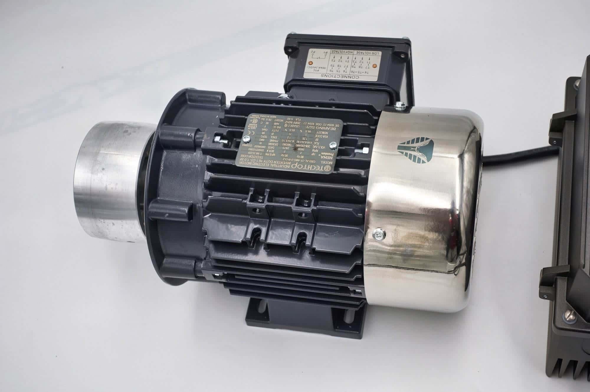 Close-up of a TechTop industrial motor's wiring connection box and nameplate on a Torus CNC grinder