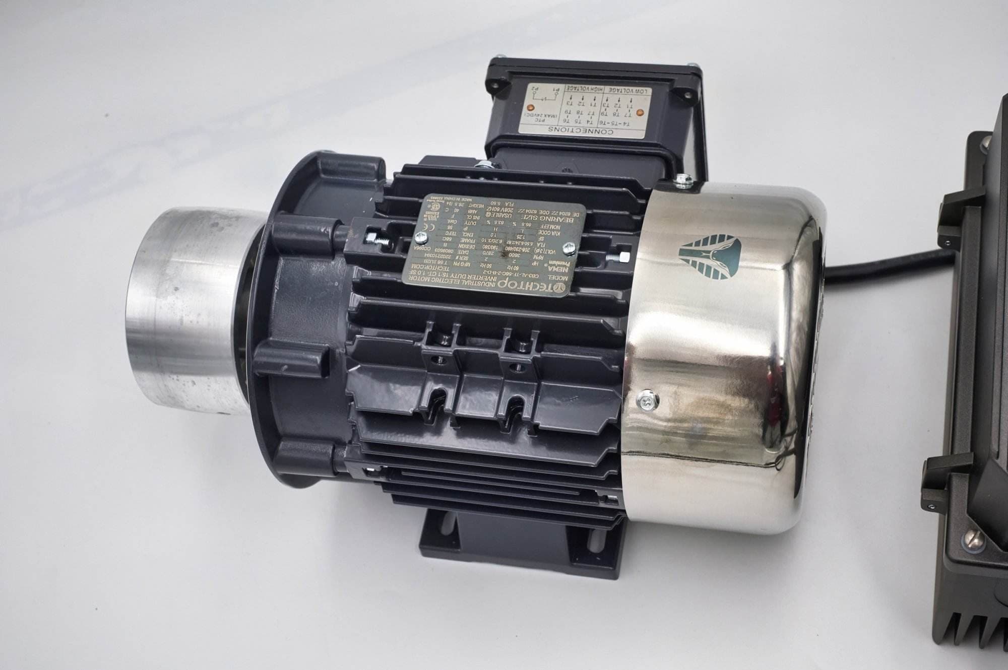 Close-up of a TechTop industrial motor's wiring connection box and nameplate on a Torus CNC grinder