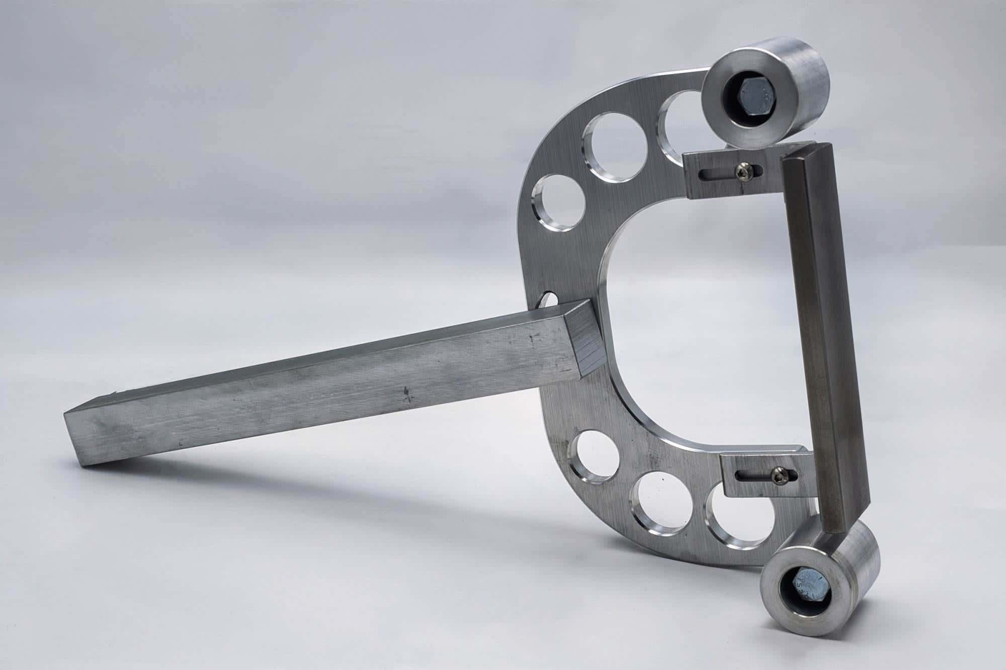 CNC aluminum wishbone bracket with paired roller mounts leaning at an angle beside its square mounting bar