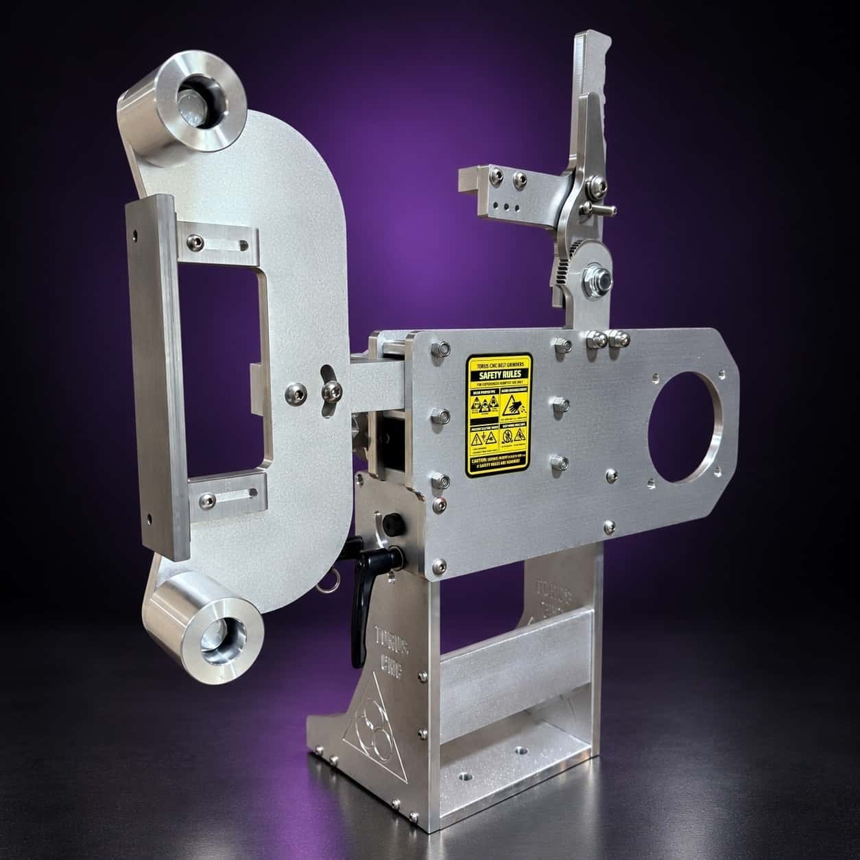 Classic aluminum 2x72 grinder, side view with flat-platen tool arm and yellow Safety Rules label, on black with a purple glow