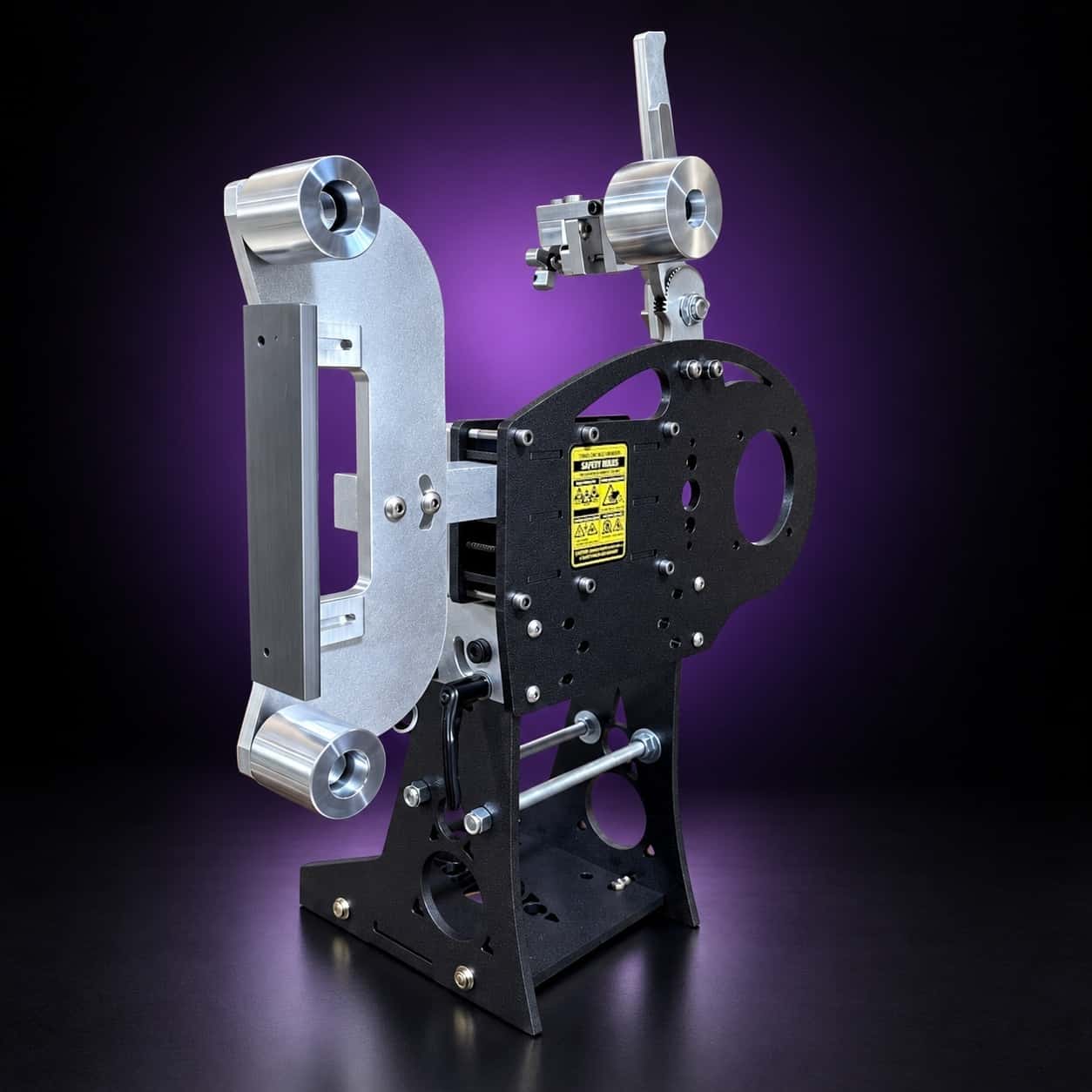 Nebula 2x72 grinder, front three-quarter view: aluminum arm, black plate, Safety Rules label, on black with a purple glow