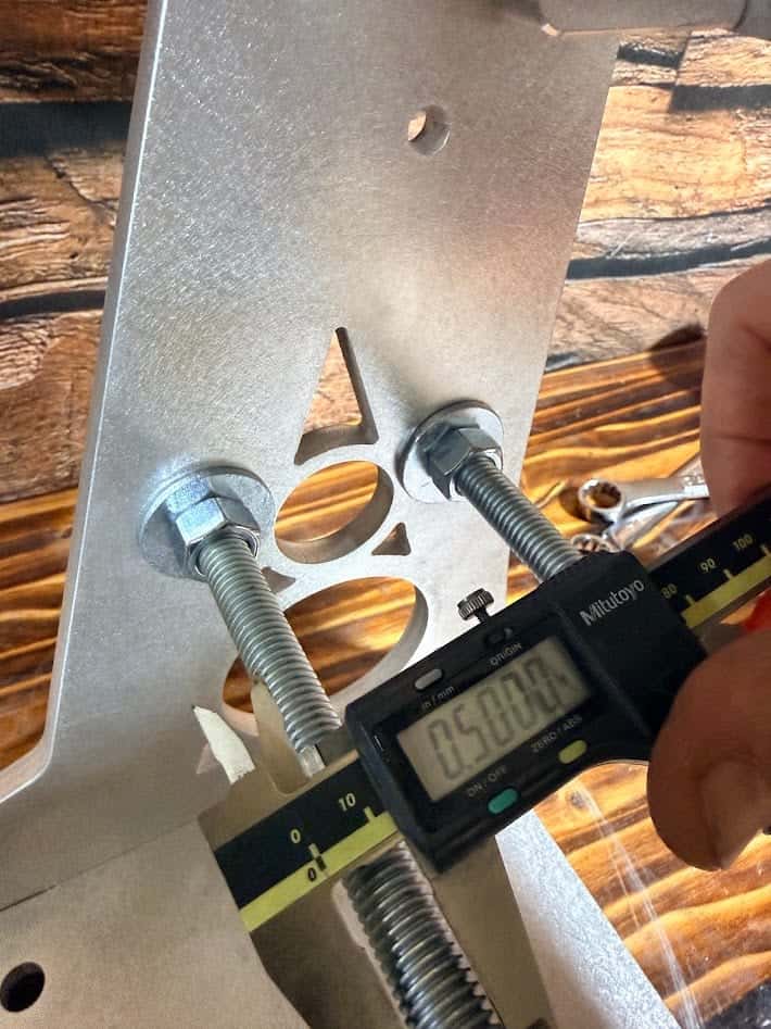 Digital caliper measuring the 0.5-inch diameter of a cross-bracing rod on the Nova grinder arm