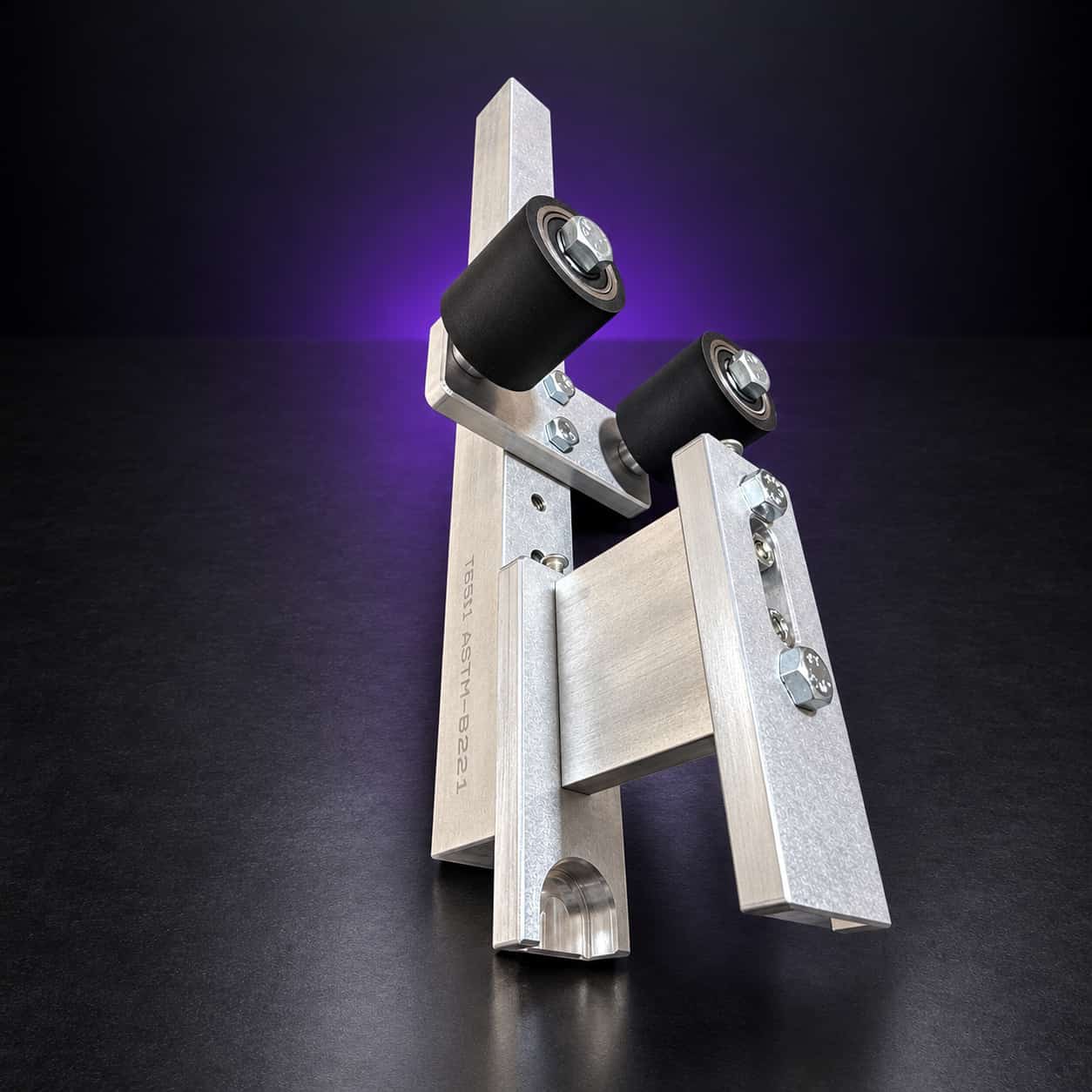 Small wheel attachment standing on end: aluminum arm, holder plate and two black rubber deflector wheels