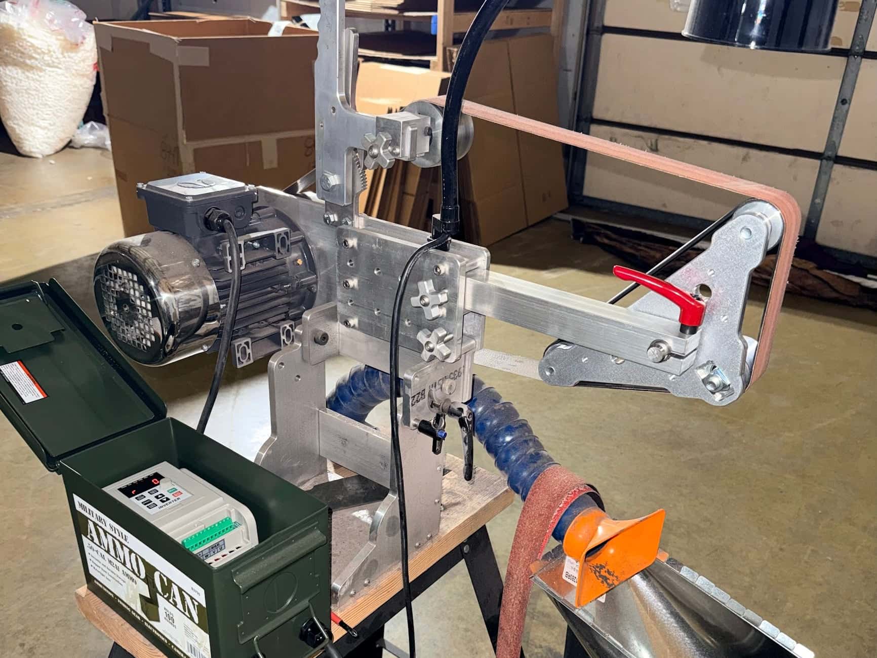 Classic aluminum grinder fitted with a motor and abrasive belt on the shop test stand