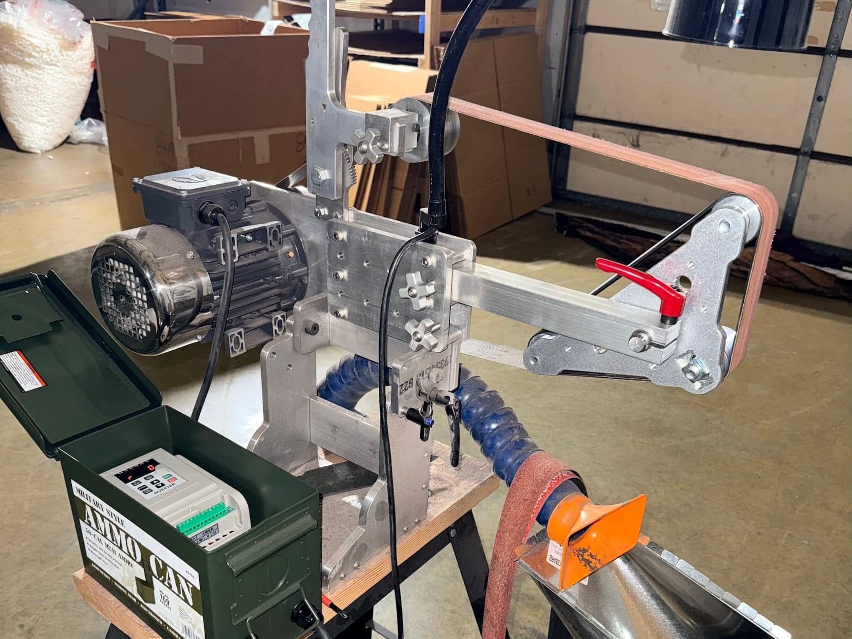 Classic aluminum grinder fitted with a motor and abrasive belt on the shop test stand