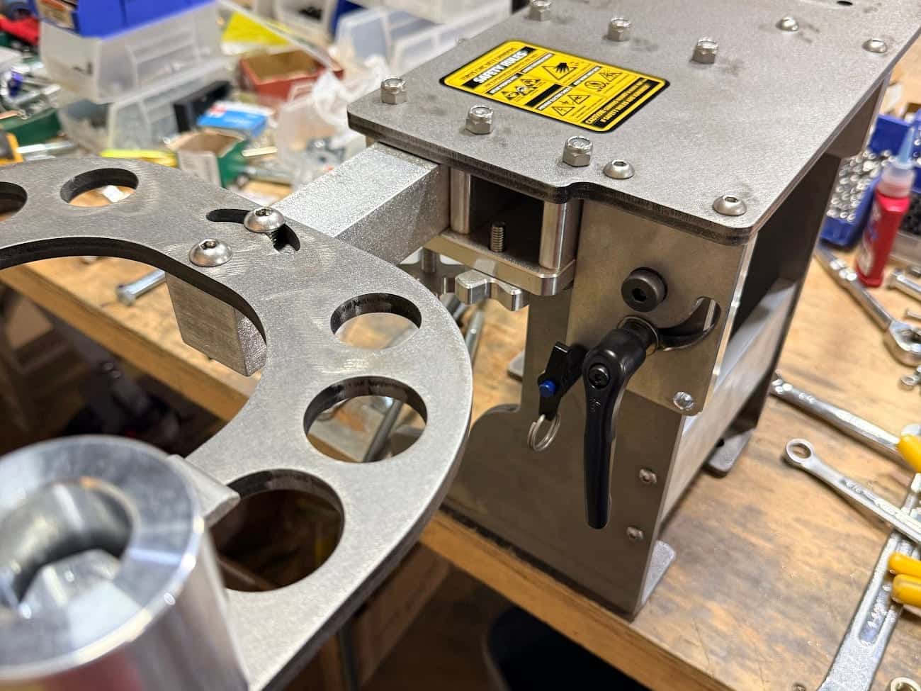 A Torus Steel 2x72 chassis half-assembled on my bench, safety label on the top plate, wrenches and a machined plate beside it