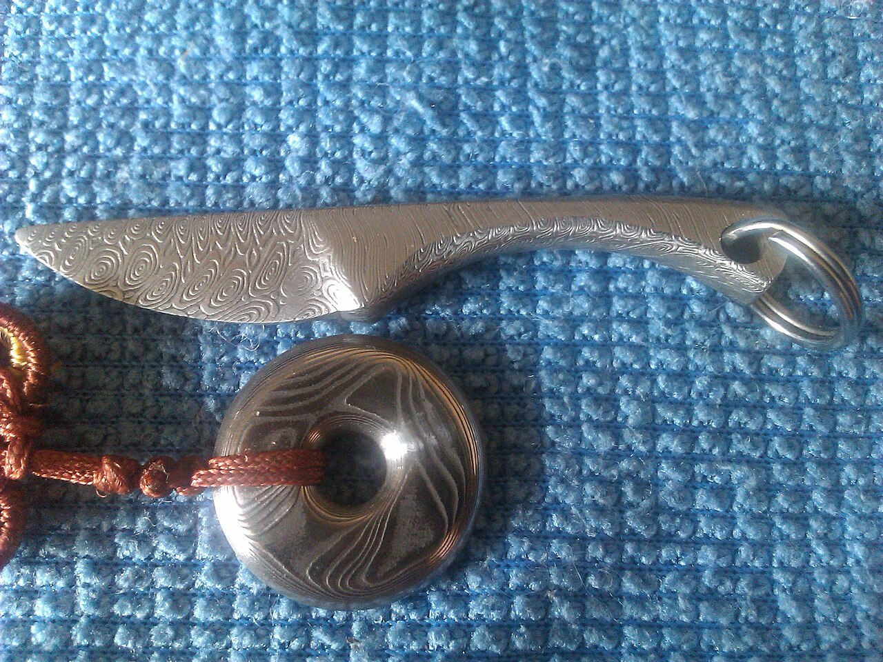Close-up of an etched pattern-welded damascus steel surface showing bright and dark layers